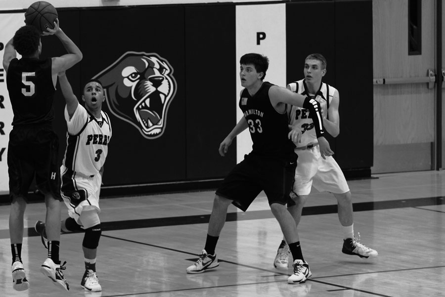 Senior guard Nathan Henderson defends a shot against a Hamilton player, with junior forward Geoffrey Vredevoogd looking on. 