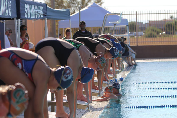Multiple girl swimmers line up in preperation for a swim meet. 