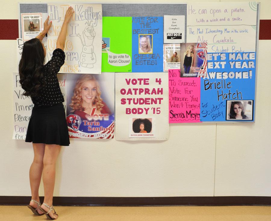 Sophomore Kaitlyn Van Klompenberg hangs an election poster in the C building.