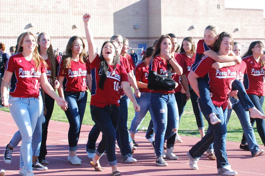 The student body cheer as Perry Varsity softball walks across the track at the spring assembly.