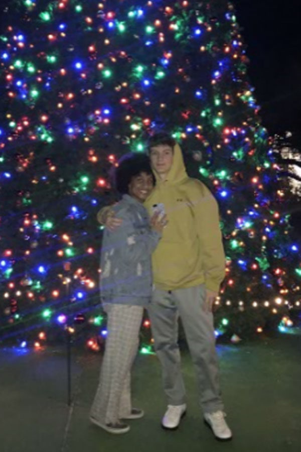Seniors Ayanna Purdie and Dalton Johnston celebrating Christmas by a lit Christmas tree