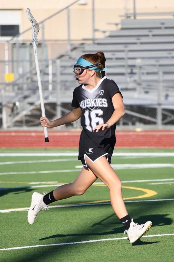 Paige Cavner (12) chases the lacrosse ball in a game. Cavner practices multiple times a week with a diverse amount of girls on the Husky team.
