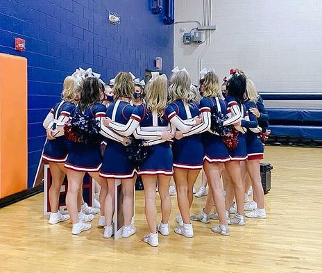 Varsity cheer huddles together before taking the mat at last weeks competition. The team placed 2nd out of 17 teams and qualified to compete at state in March.