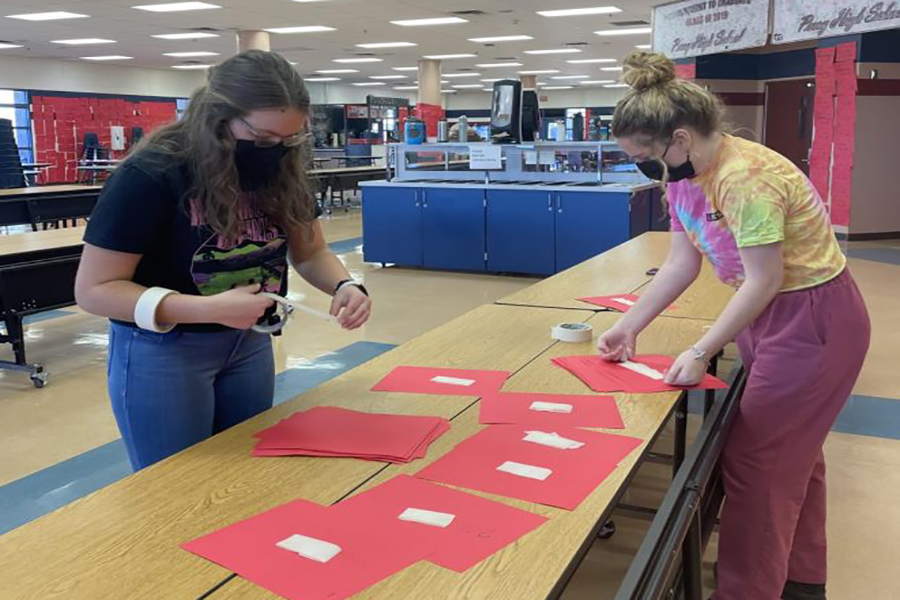 Ella Hanks and Bridget Pitts from StuGo working on putting up the Valentines Day hearts with all the teachers and students names on them.