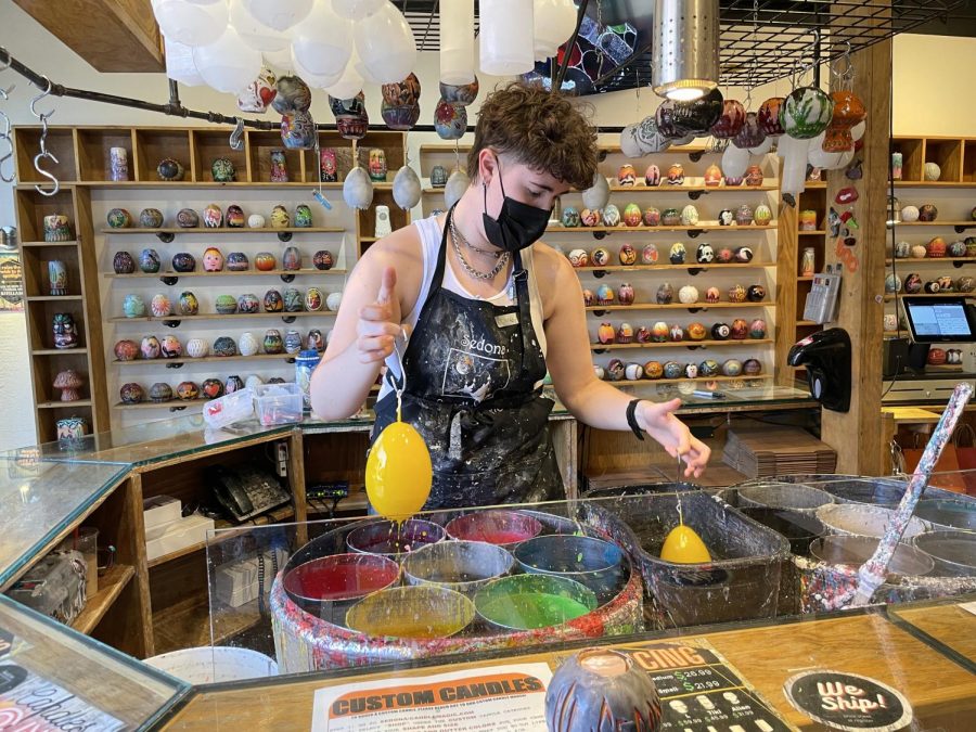 Candle artist Jules dipping candles into vats of colored wax at Sedona Candle Magic. She makes an average of 20-25 candles each day. 