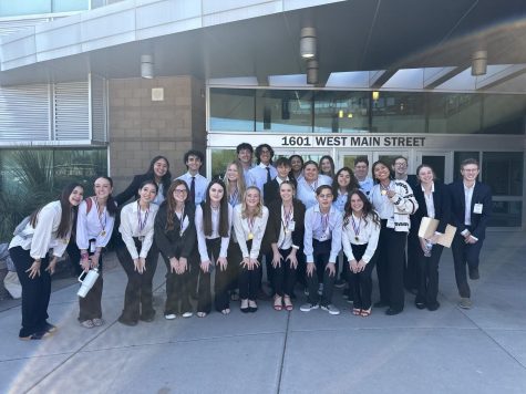 HOSA competitors line up outside the building they just competed in. Each member is holding the award they earned. 