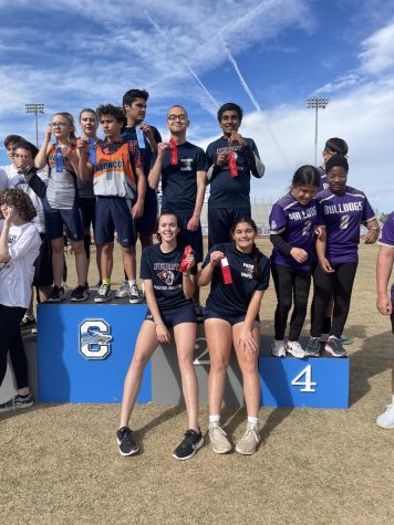 Unified track team standing on podiums holding medals  