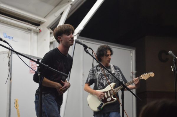 Senior vocalist Sam Myers sings while Senior Dax Gardner plays the guitar in front of an audience at the Homecoming Carnival. In the past, Myers dreamed of being a singer and learned the guitar to accompany his position.