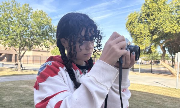 Junior Sarina Frink is taking a photo of the outdoor  landscape using a film camera. Frink uses film photography as an outlet of self expression and enjoys adding a nostalgic style.