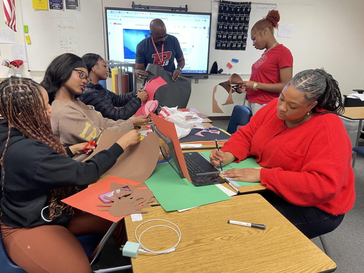 (Left to right) Skyler Alfred, Alivia Morrow, AP World History teacher John Prothro, student, student, student decorate a poster for black history month. Every year during February, BSU and BGE get together to create a poster board celebrating black history month. 
